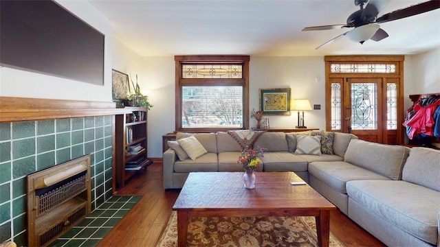 living room with ceiling fan, dark wood-type flooring, a wealth of natural light, and a tile fireplace