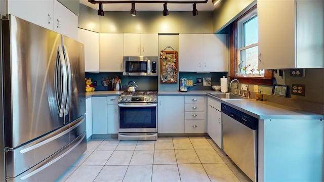 kitchen featuring a sink, stainless steel appliances, white cabinetry, track lighting, and light tile patterned flooring