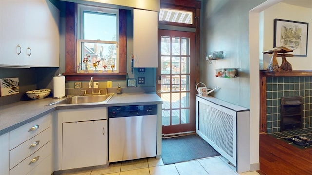 kitchen featuring light tile patterned floors, a sink, white cabinetry, light countertops, and dishwasher