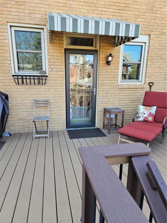 view of exterior entry featuring a wooden deck and brick siding