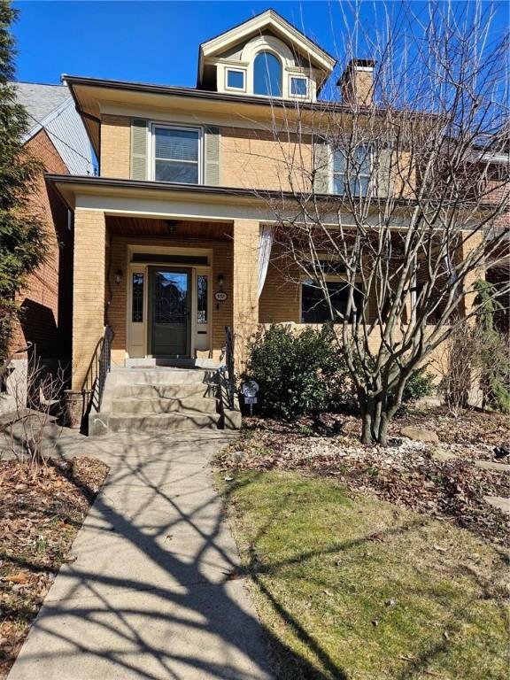 american foursquare style home featuring brick siding and a chimney