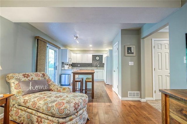 interior space featuring white appliances, visible vents, light wood-style floors, white cabinets, and backsplash