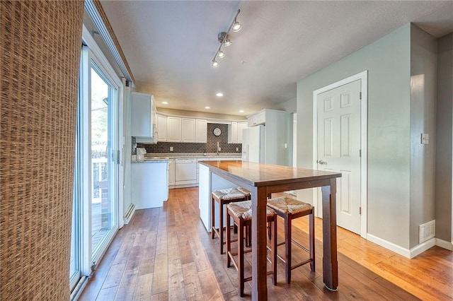 kitchen with white appliances, visible vents, decorative backsplash, and light wood-style floors