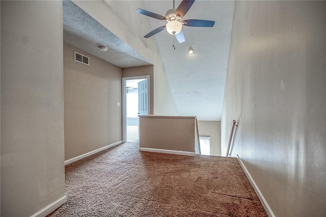 carpeted spare room featuring plenty of natural light, baseboards, visible vents, and a textured ceiling