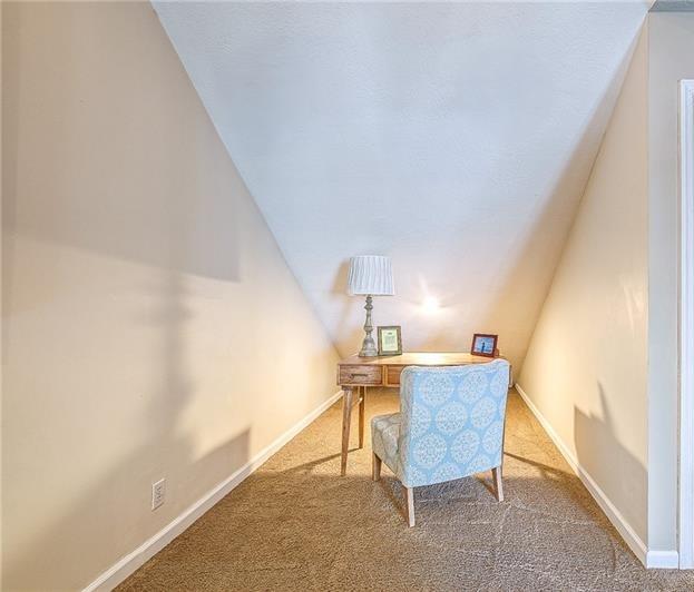 office area featuring carpet, vaulted ceiling, and baseboards