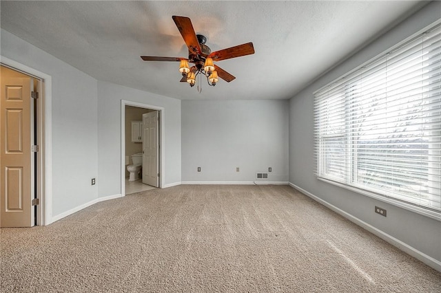 spare room featuring a ceiling fan, visible vents, light carpet, and baseboards