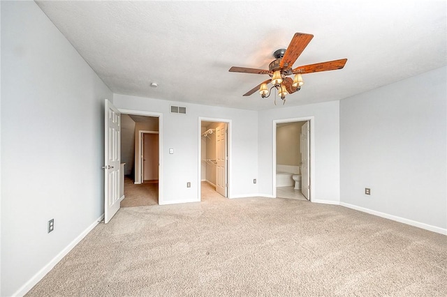 unfurnished bedroom featuring light carpet, baseboards, visible vents, a spacious closet, and a closet