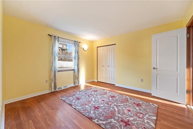 interior space with visible vents, a closet, baseboards, and wood finished floors