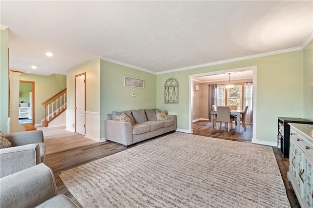 living area featuring stairs, crown molding, baseboards, and wood finished floors