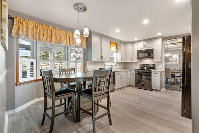 kitchen with black appliances, light wood-style floors, backsplash, and light countertops