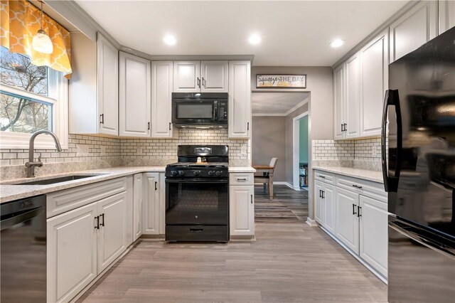 kitchen featuring black appliances, light wood-style flooring, white cabinets, and a sink