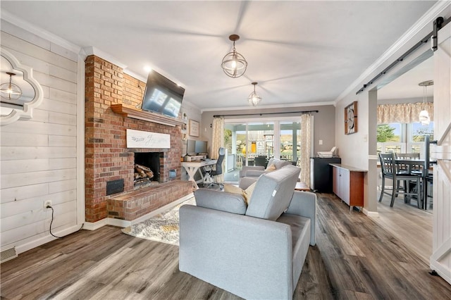 living area featuring ornamental molding, a brick fireplace, and wood finished floors