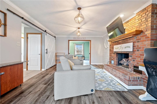 living area with a barn door, baseboards, ornamental molding, wood finished floors, and a brick fireplace