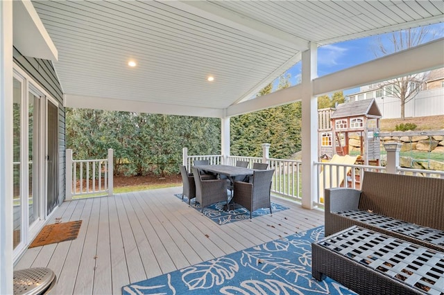 wooden deck with a playground and outdoor dining space