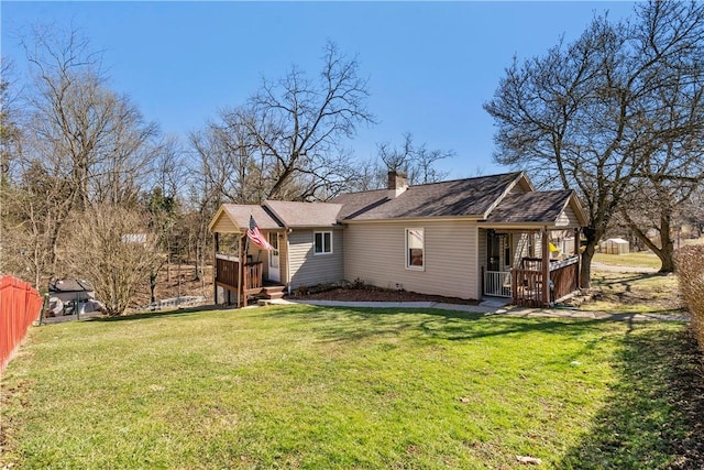 rear view of property with fence, a chimney, a wooden deck, and a lawn