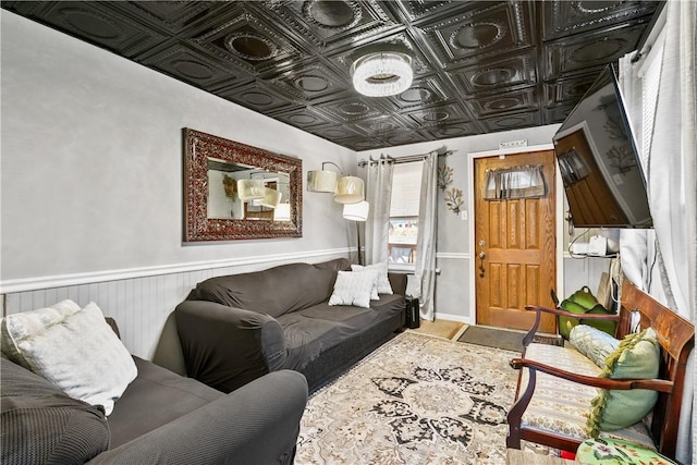 living room with a wainscoted wall and an ornate ceiling