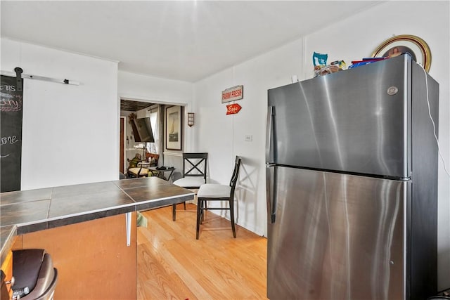 kitchen with tile counters, freestanding refrigerator, wood finished floors, and a barn door