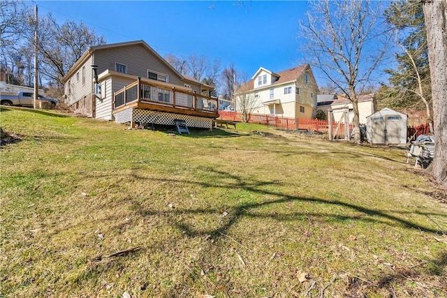 back of property with a storage unit, a lawn, fence, a deck, and an outdoor structure