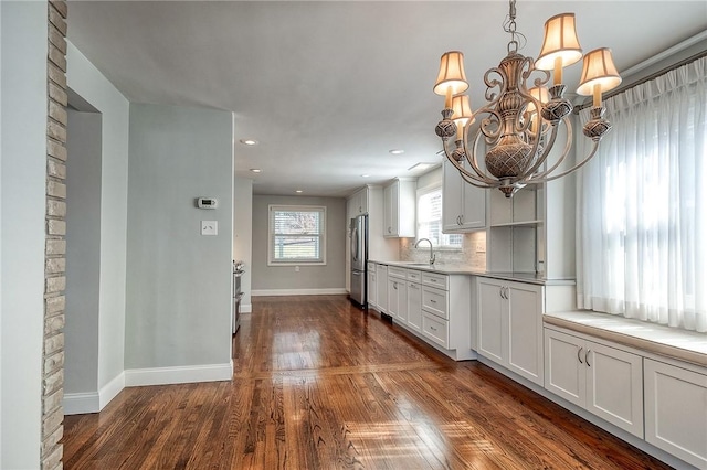 kitchen featuring dark wood-style flooring, a sink, baseboards, freestanding refrigerator, and tasteful backsplash