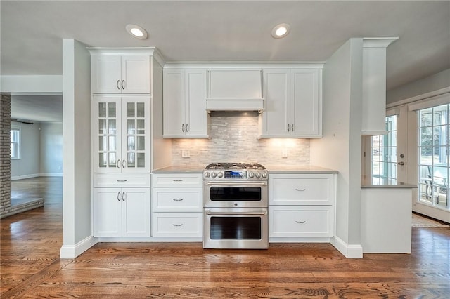 kitchen with dark wood-style floors, double oven range, white cabinets, and backsplash