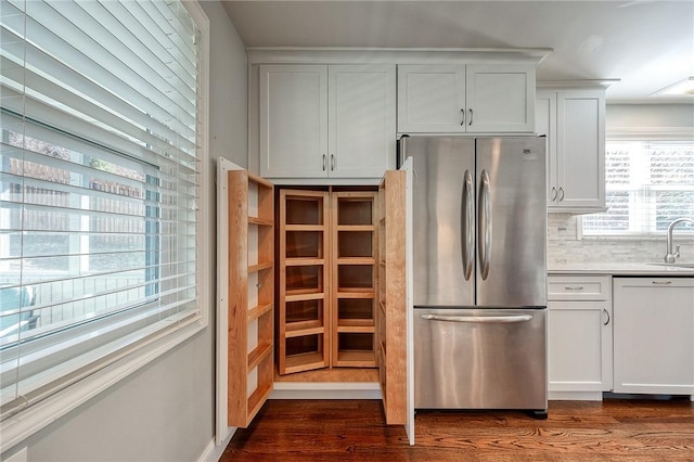 kitchen featuring dark wood finished floors, decorative backsplash, freestanding refrigerator, white dishwasher, and a sink