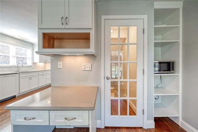 interior space with white cabinets, stainless steel microwave, wood finished floors, white dishwasher, and light countertops