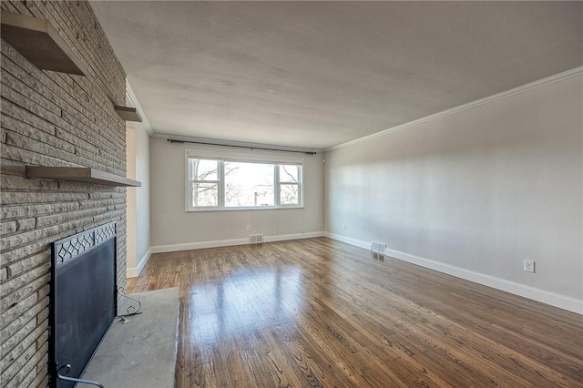 unfurnished living room featuring ornamental molding, visible vents, a fireplace, and wood finished floors