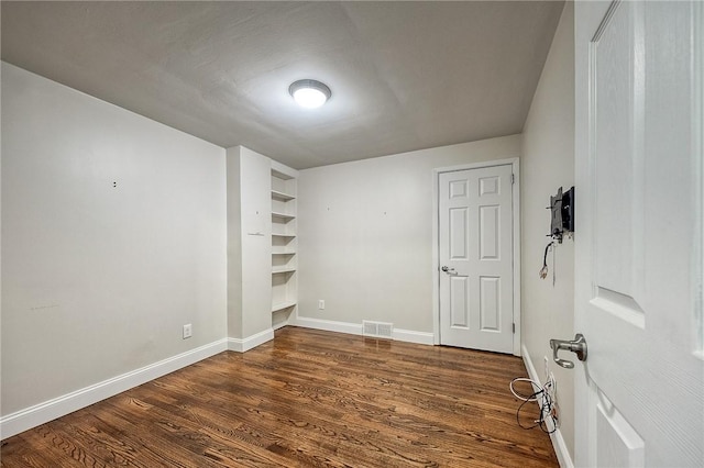 unfurnished room with dark wood-style floors, visible vents, and baseboards