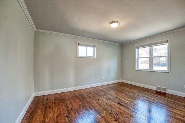 empty room with dark wood-style floors, visible vents, crown molding, and baseboards