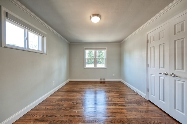 spare room with crown molding, dark wood finished floors, visible vents, and baseboards