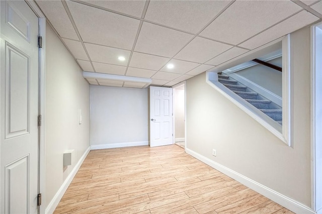 finished below grade area featuring a paneled ceiling, recessed lighting, wood finished floors, baseboards, and stairs