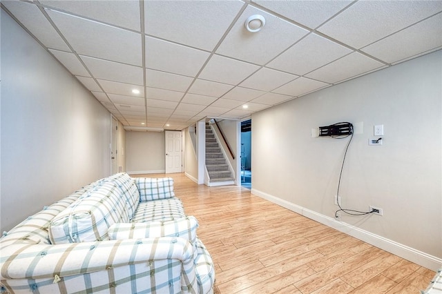 unfurnished living room with a paneled ceiling, light wood-style floors, stairs, and baseboards