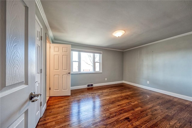 unfurnished bedroom featuring ornamental molding, visible vents, dark wood finished floors, and baseboards