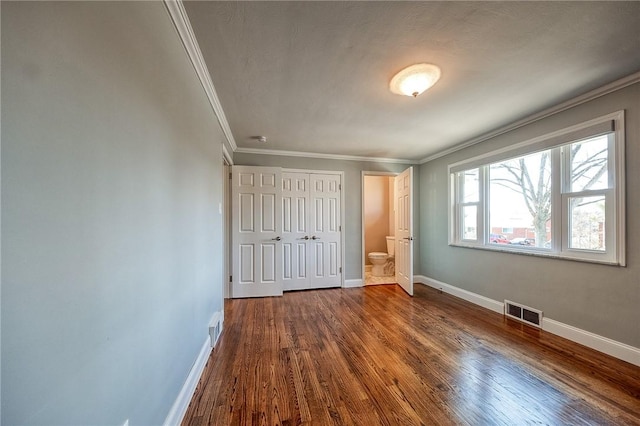 unfurnished bedroom featuring dark wood-style floors, baseboards, visible vents, and ornamental molding