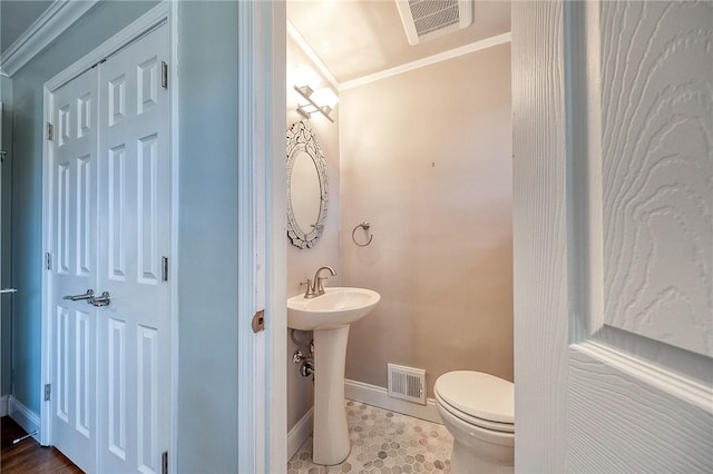 half bath with toilet, baseboards, visible vents, and crown molding