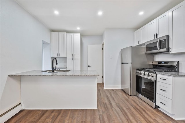 kitchen featuring stainless steel appliances, a baseboard heating unit, a sink, and light stone counters