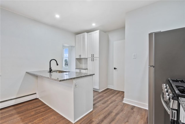 kitchen featuring dark wood-style floors, light stone counters, stainless steel appliances, white cabinetry, and a sink