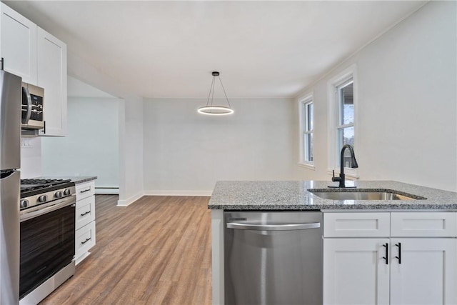 kitchen with stainless steel appliances, white cabinets, a sink, and light wood-style flooring