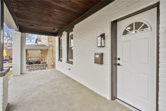 view of exterior entry with covered porch and brick siding