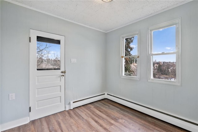 interior space featuring wood finished floors, baseboard heating, crown molding, a textured ceiling, and a baseboard heating unit