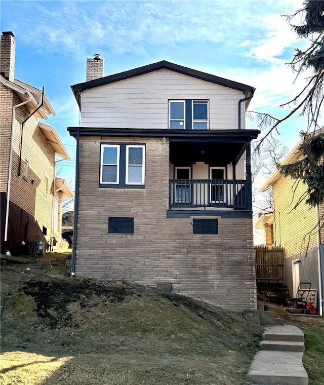 rear view of house with a balcony and a chimney