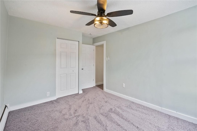 unfurnished bedroom with carpet, a closet, baseboard heating, ceiling fan, and baseboards