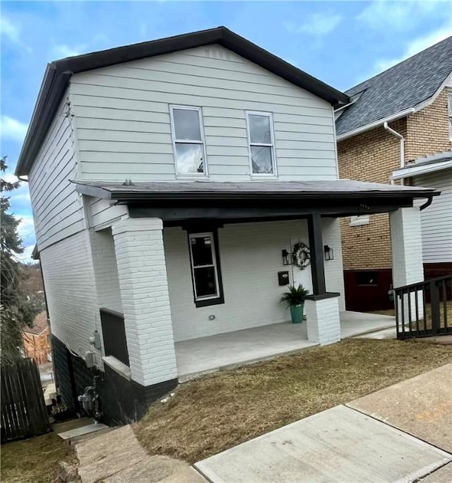 rear view of property featuring fence and brick siding