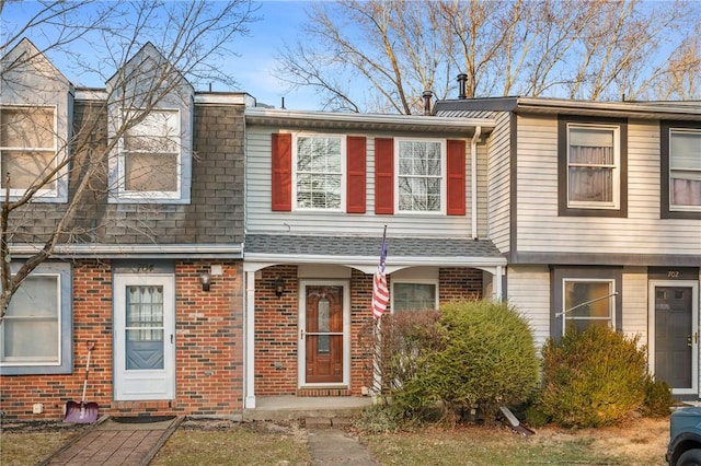 view of property with roof with shingles and brick siding