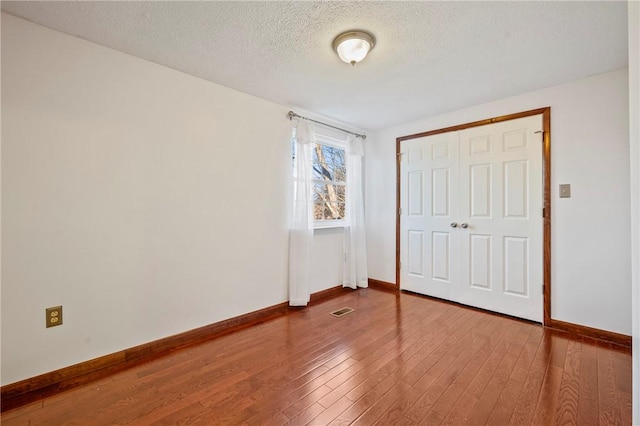 unfurnished bedroom featuring wood-type flooring, visible vents, and baseboards