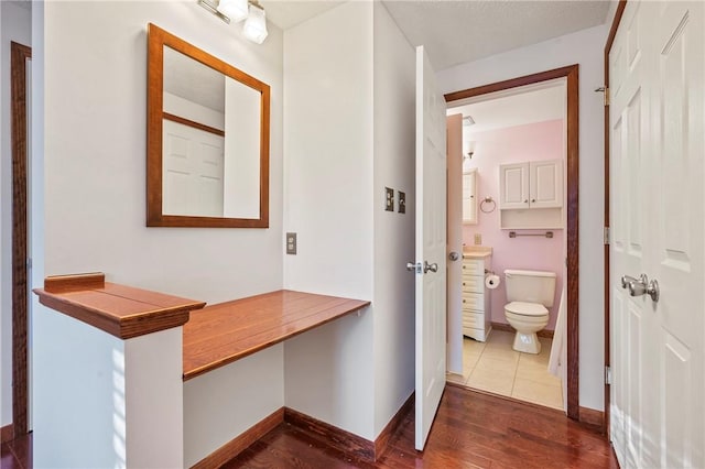 half bath featuring vanity, wood finished floors, toilet, and baseboards