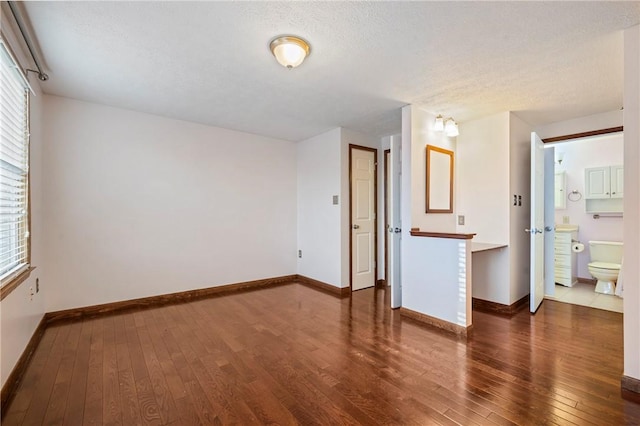 unfurnished room with baseboards, a textured ceiling, and hardwood / wood-style floors