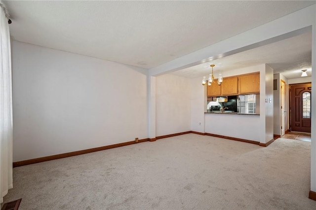 unfurnished living room with baseboards, visible vents, a chandelier, and light colored carpet