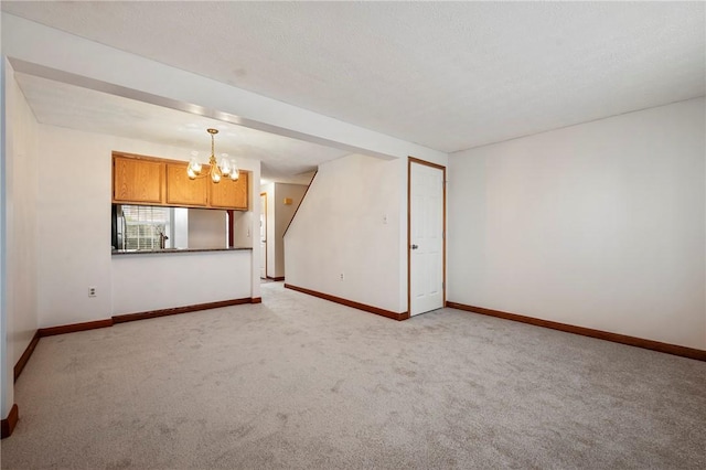 spare room with light carpet, an inviting chandelier, baseboards, and a textured ceiling