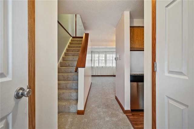 stairway with carpet floors, a textured ceiling, and baseboards